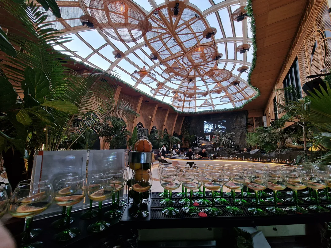 Aranjament de pahare de sticlă pregătite pe bar, într-o seră amenajată pentru eveniment