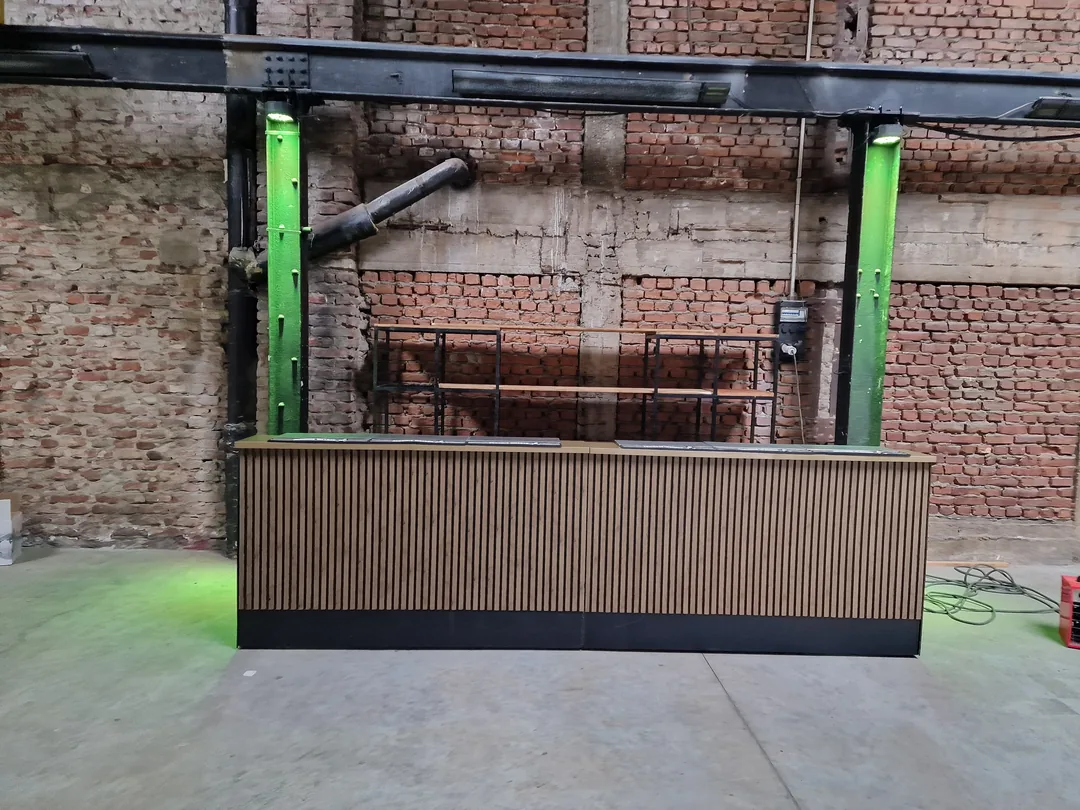 Bar mobil premium din lemn cu riflaje, montat într-un spațiu industrial înainte de eveniment