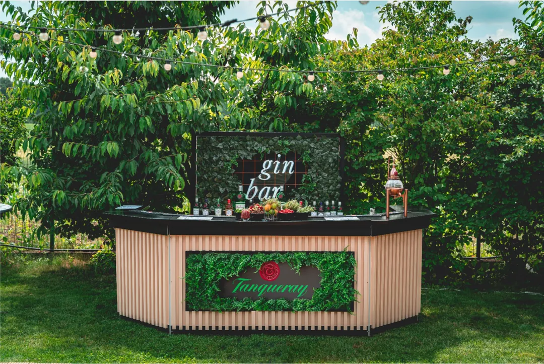 Gin bar Tanqueray cu perete vegetal, amenajat într-o grădină la un eveniment privat