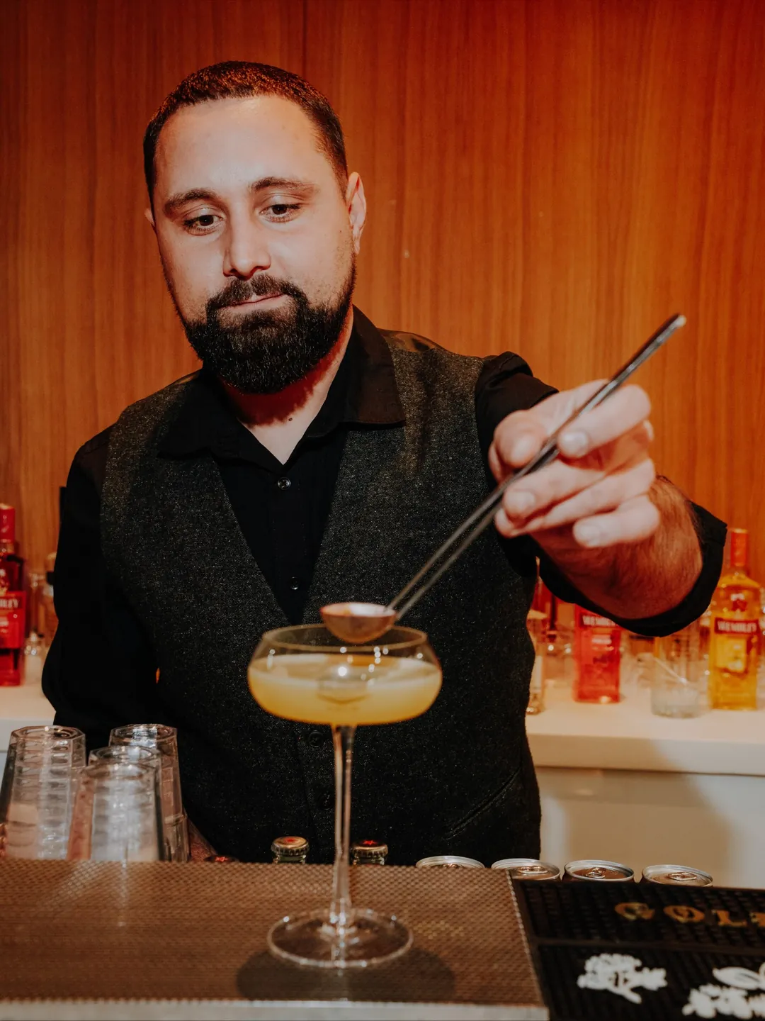 Barman Cofftails Events strecurând un cocktail într-un pahar coupe