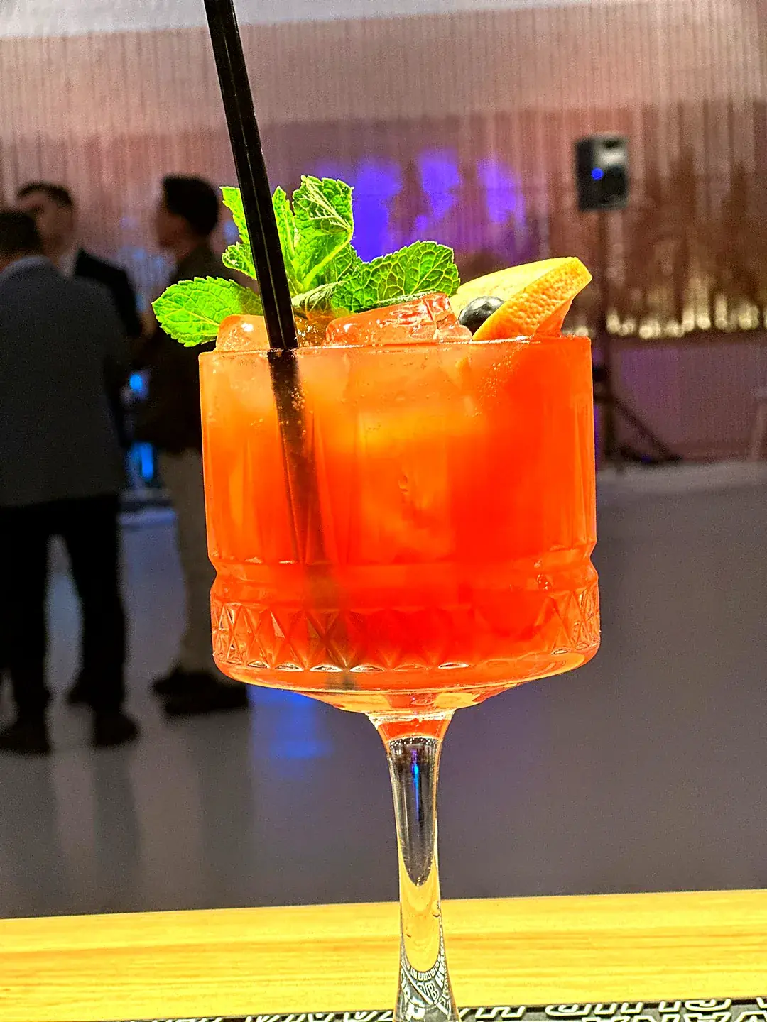 Cocktail roșu vibrant cu mentă, grepfrut și fructe de pădure, servit la un eveniment corporate