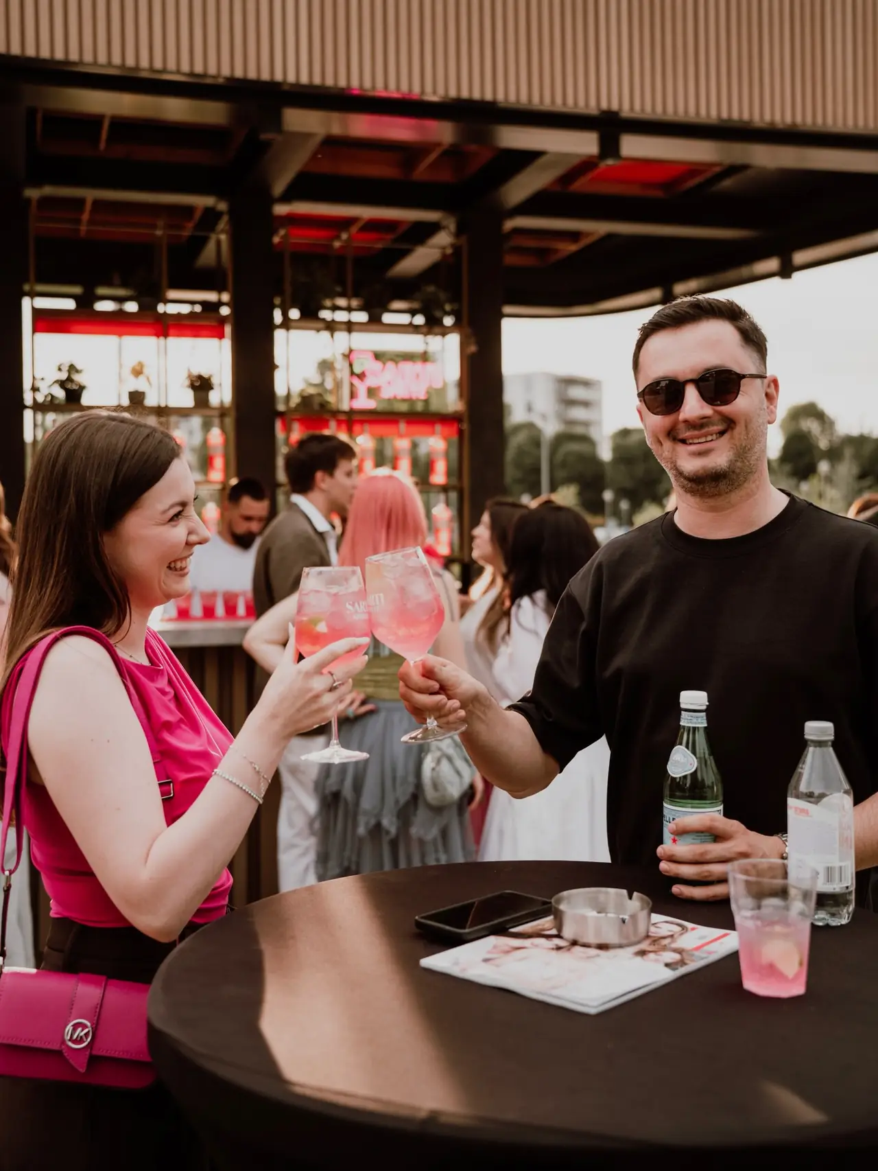 Invitați ciocnind cocktailuri pe terasa unui eveniment Cofftail's Events, în plină zi