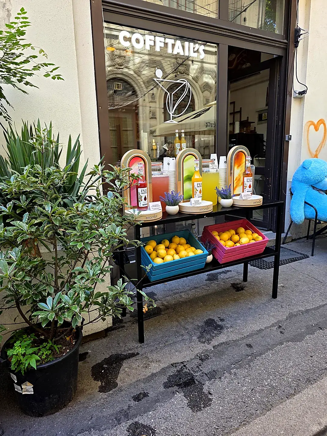 Stand de limonadă artizanală cu dispensere de limonadă și lădițe cu lămâi, în fața cafenelei Cofftails